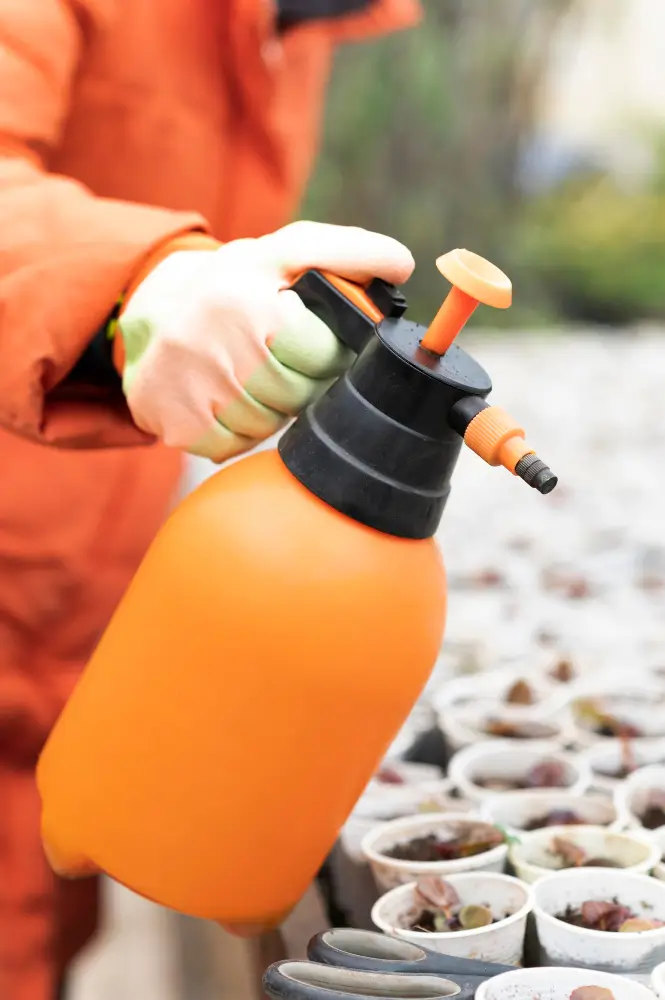 Persona aplicando productos fitosanitarios con un pulverizador manual en un vivero.